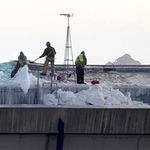 Workers clear snow from the roof of the Metrodome
